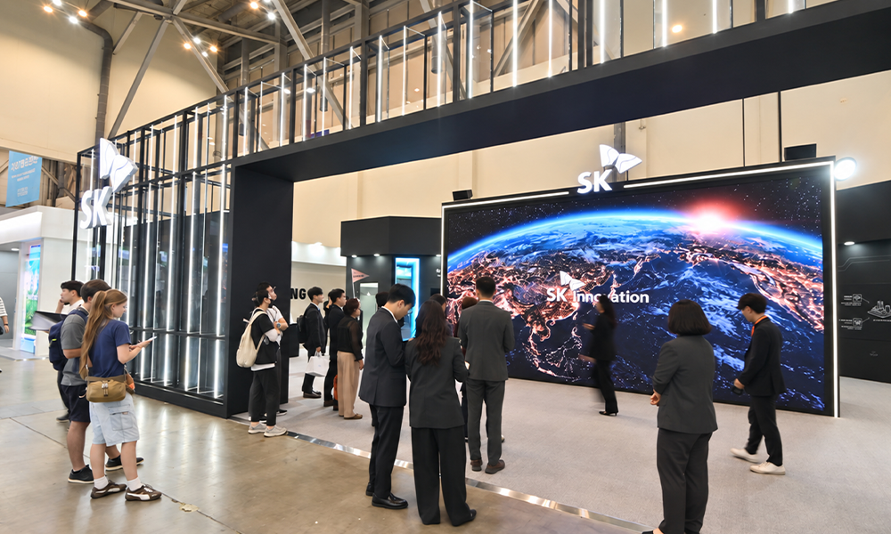 '2026 기후산업국제박람회(WCE)' SK 전시관 입구. 대형 스크린에 지구 야경과 'SK innovation' 로고가 표시되어 있고, 관람객들이 줄지어 전시관을 둘러보고 있다