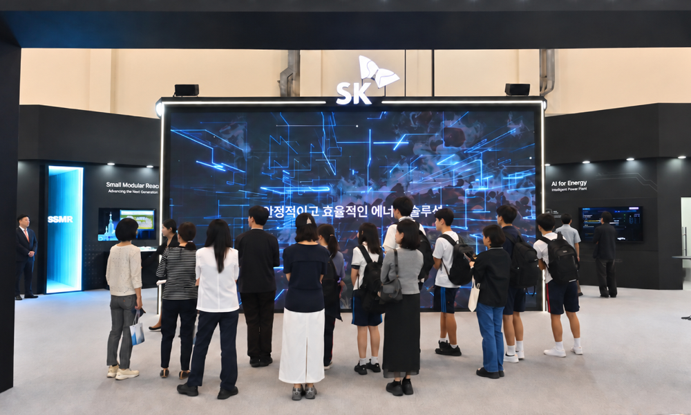 'WCE 2026' SK 전시관 대형 스크린에 '안정적이고 효율적인 에너지 솔루션'이라는 문구와 네트워크 그래픽이 표시되어 있고, 관람객들이 모여 화면을 보고 있다. 양쪽으로 SMR, AI for Energy 존이 보인다
