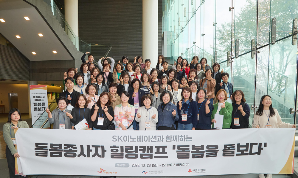 SK이노베이션 돌봄종사자 재충전 힐링캠프 ‘돌봄을 돌보다’ 참가자들이 현수막 앞에서 하트 손동작으로 기념사진을 찍고 있다